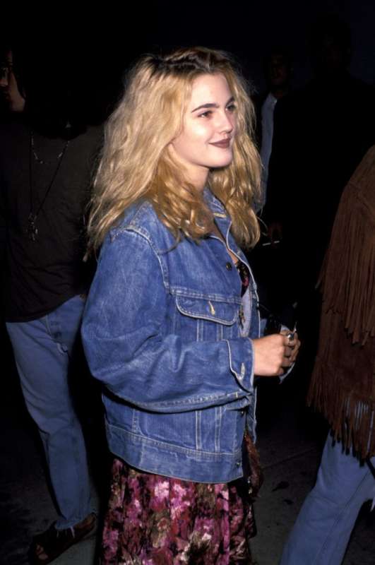 Drew Barrymore con giacca di jeans e abito floreale.